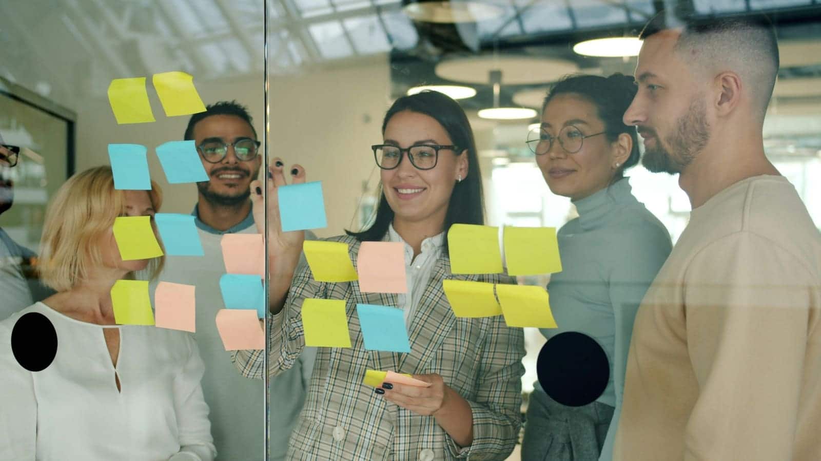 Team arranging sticky notes on a glass wall during a planning session