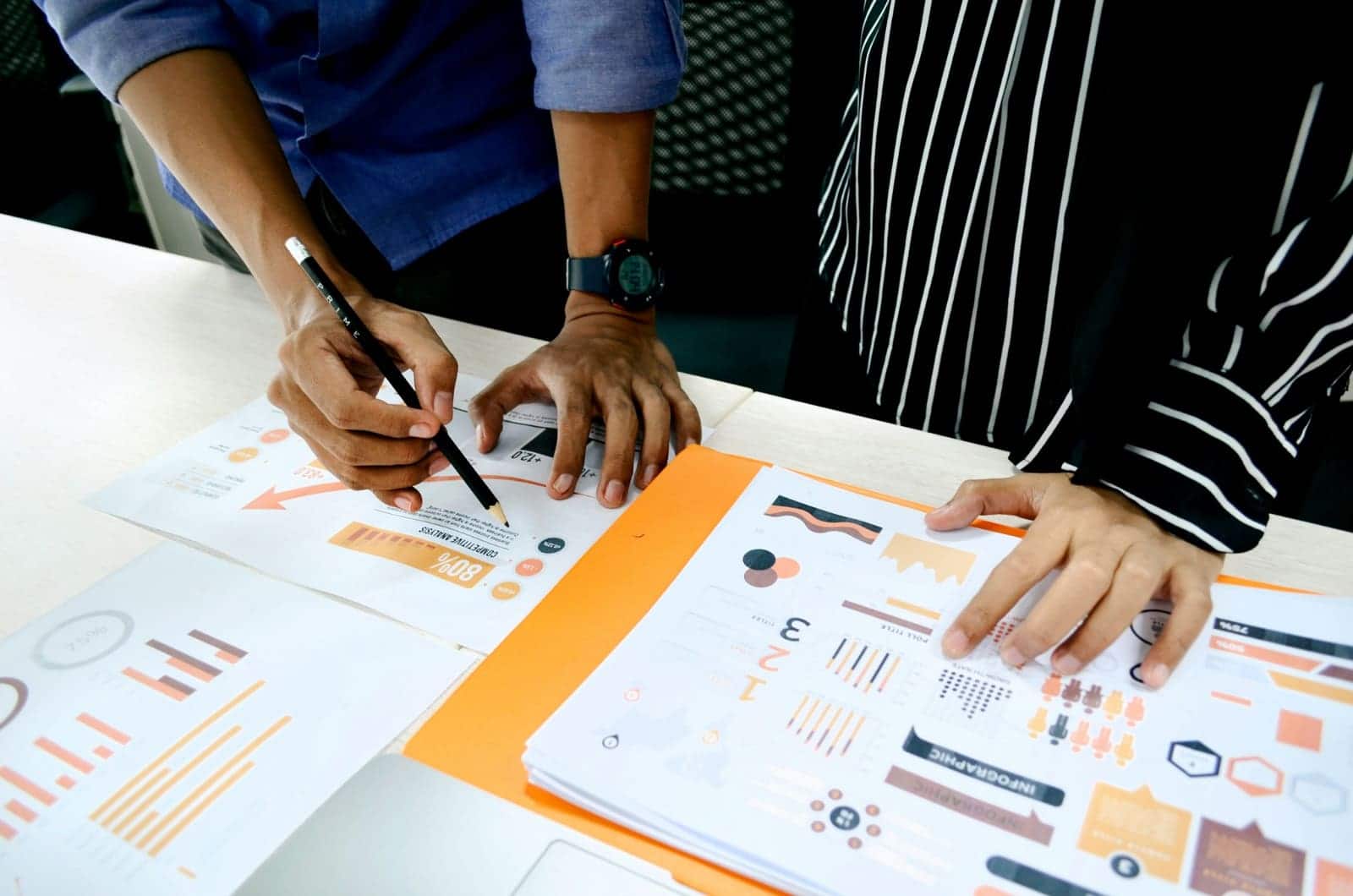 Two people reviewing printed charts and analysis at a desk