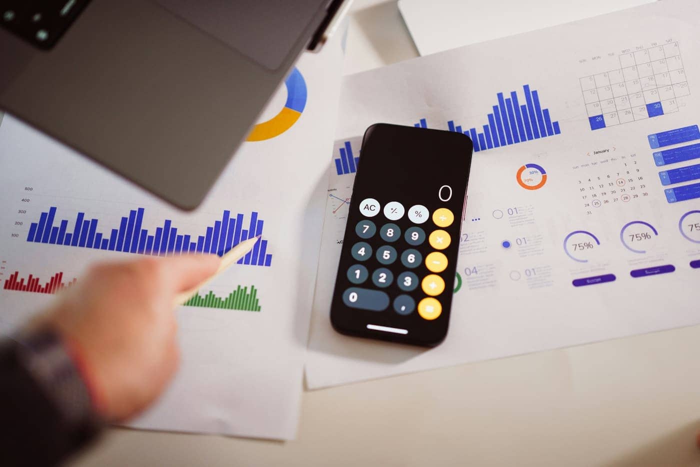 Calculator on a phone resting on printed spending charts